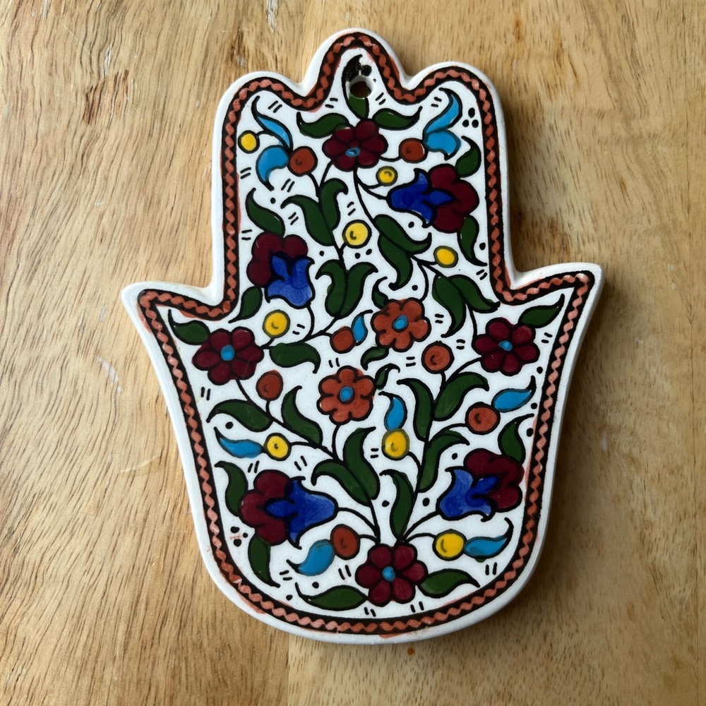 Ceramic hand / hamsa with painted flowers can placed on wall or left on table.